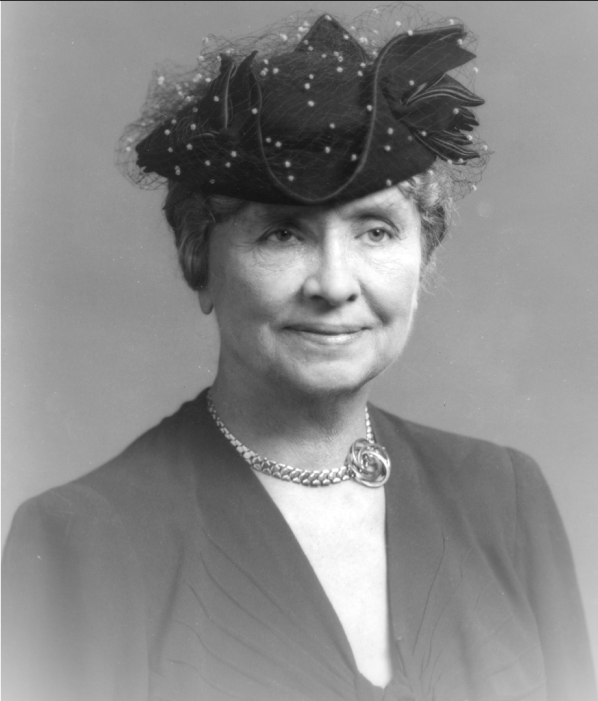 A studio portrait of Helen Keller wearing a dark hat decorated with netting.